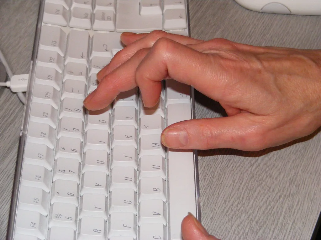 A hand typing on a white computer keyboard