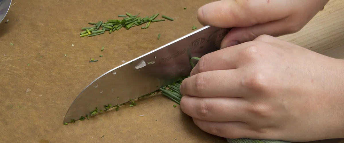 Chopping chives with a chef's knife on a cutting board