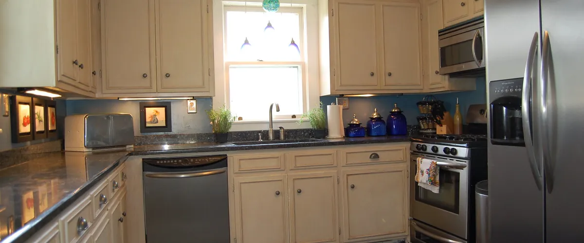 Home kitchen with cream cabinets and stainless steel appliances (stock photo)