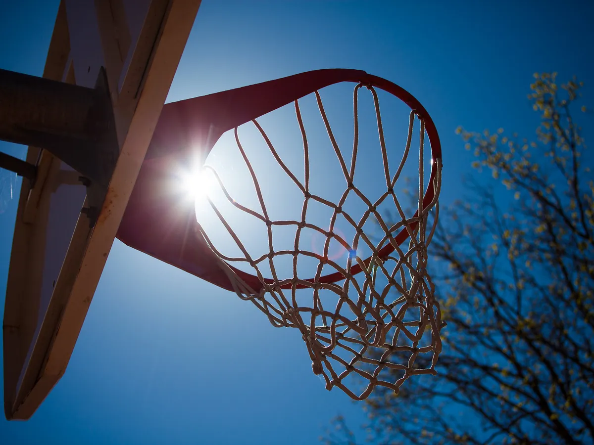 A basketball hoop and net seen from below against a blue sky