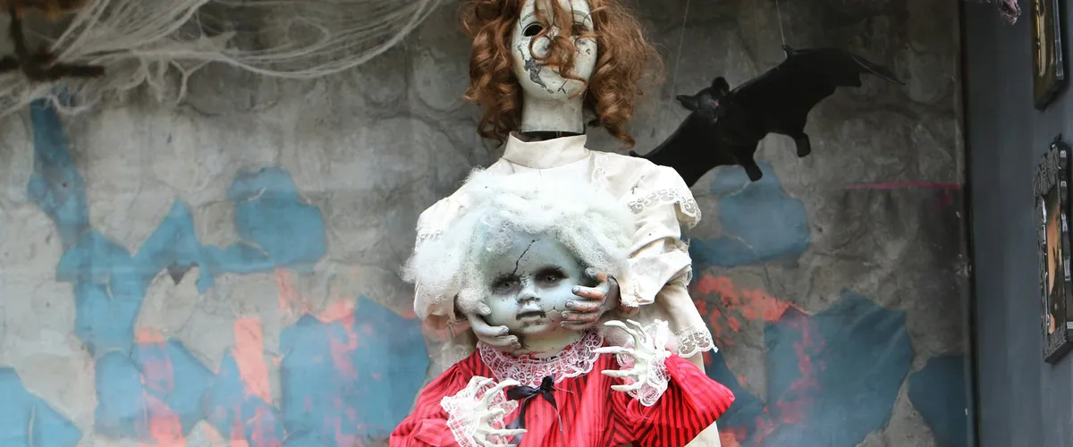 Two creepy dolls with tattered clothing and cobwebs (stock photo, not affiliated with Spirit Halloween)