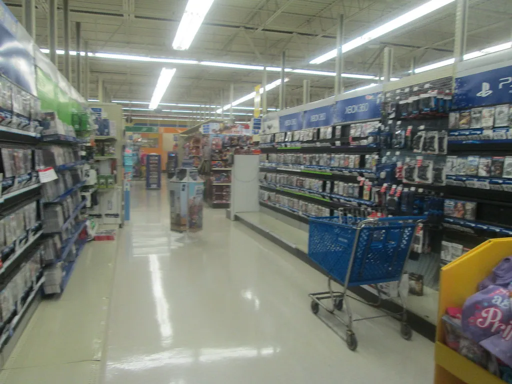 A toy store's video game and electronics aisle with a shopping cart